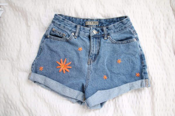 blue denim shorts hand embroidered with a big orange flower and 5 smaller orange flowers