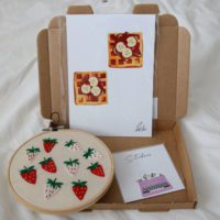 Overview of a second sample mystery box containing a strawberry hoop, waffle print and typewriter sticker