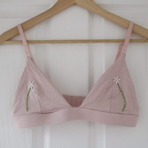 close up of the pink bralette with 2 hand embroidered daisies
