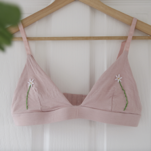 A pink bralette hand embroidered with daisies