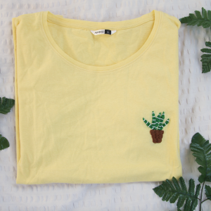 A yellow t-shirt hand embroidered with an aloe vera plant