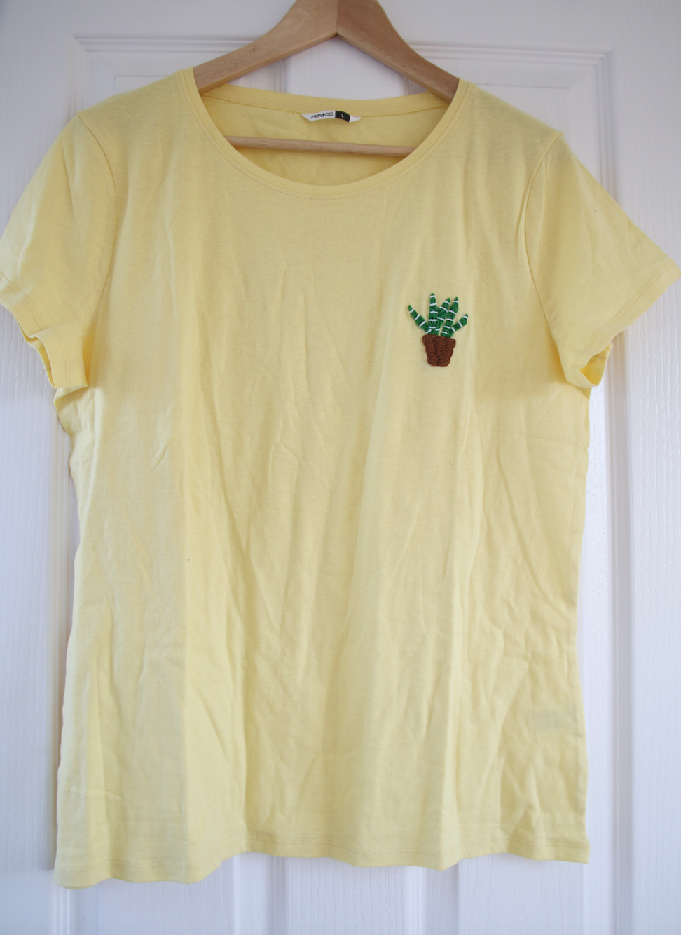 A yellow t-shirt hand embroidered with an aloe vera plant
