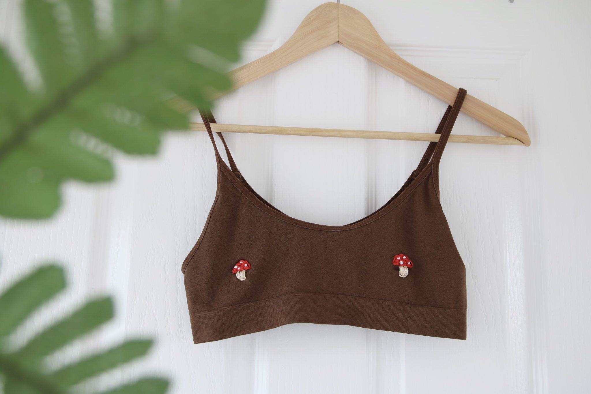 A brown bralette hand embroidered with toadstool mushrooms