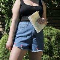 girl wearing blue denim shorts hand embroidered with 4 red toadstools at the hem