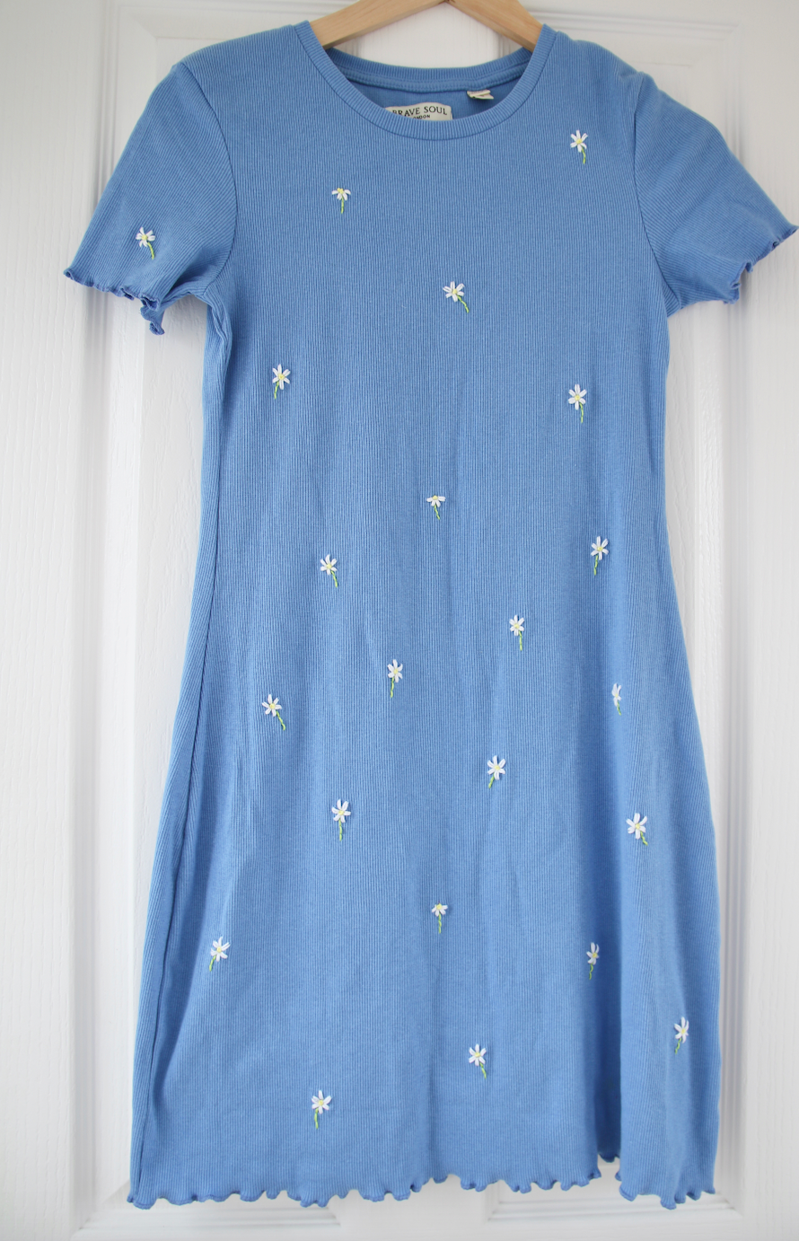 A blue body con dress hand embroidered with white daisies