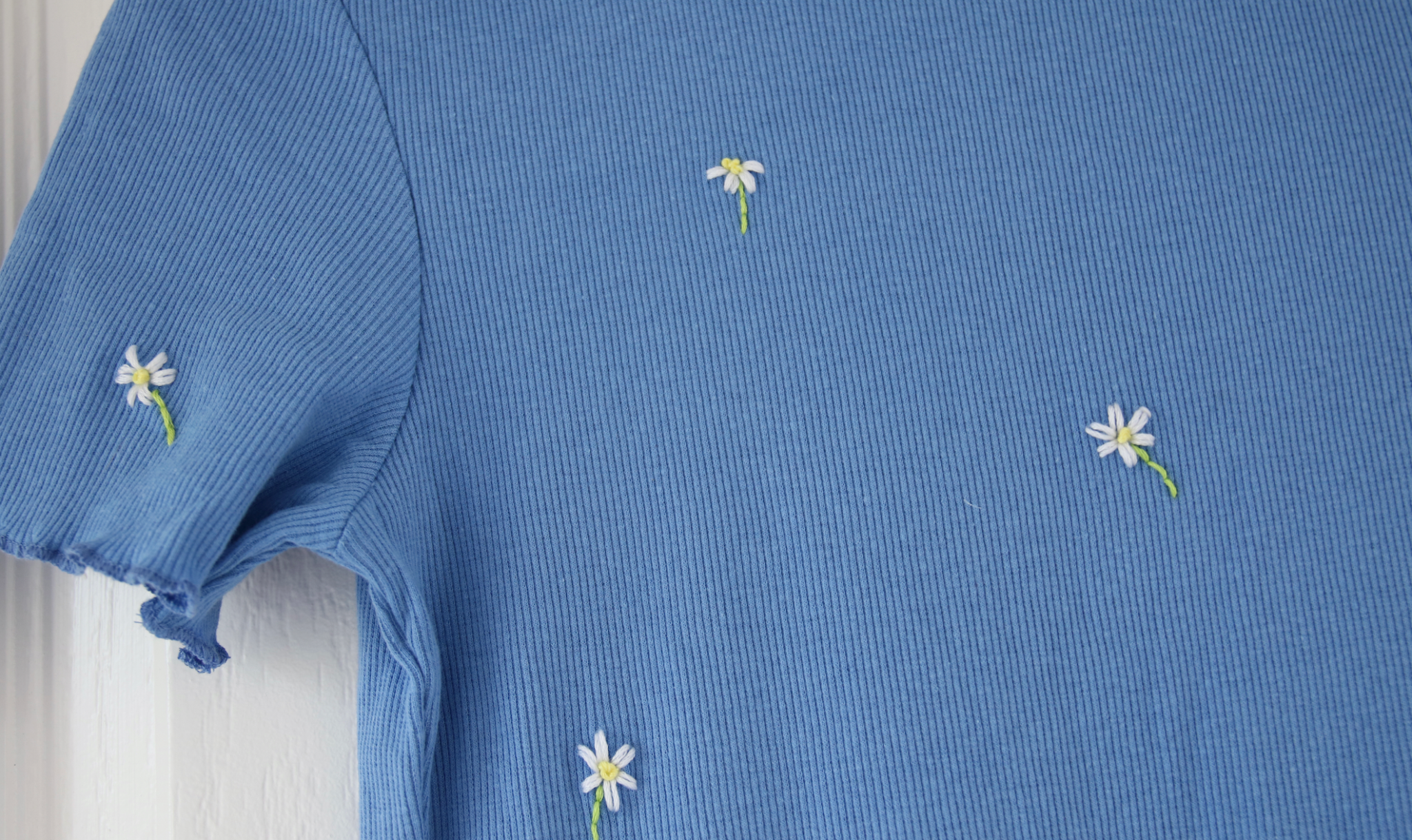White daisies embroidered onto a blue body con dress