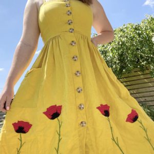 brunette model wearing a yellow dress with hand embroidered red poppies
