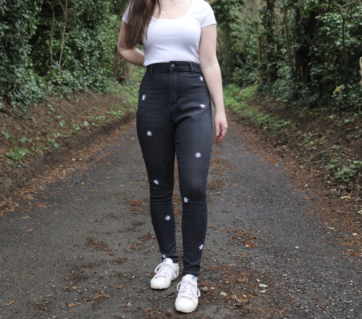 Black skinny jeans hand embroidered with white daisies all over