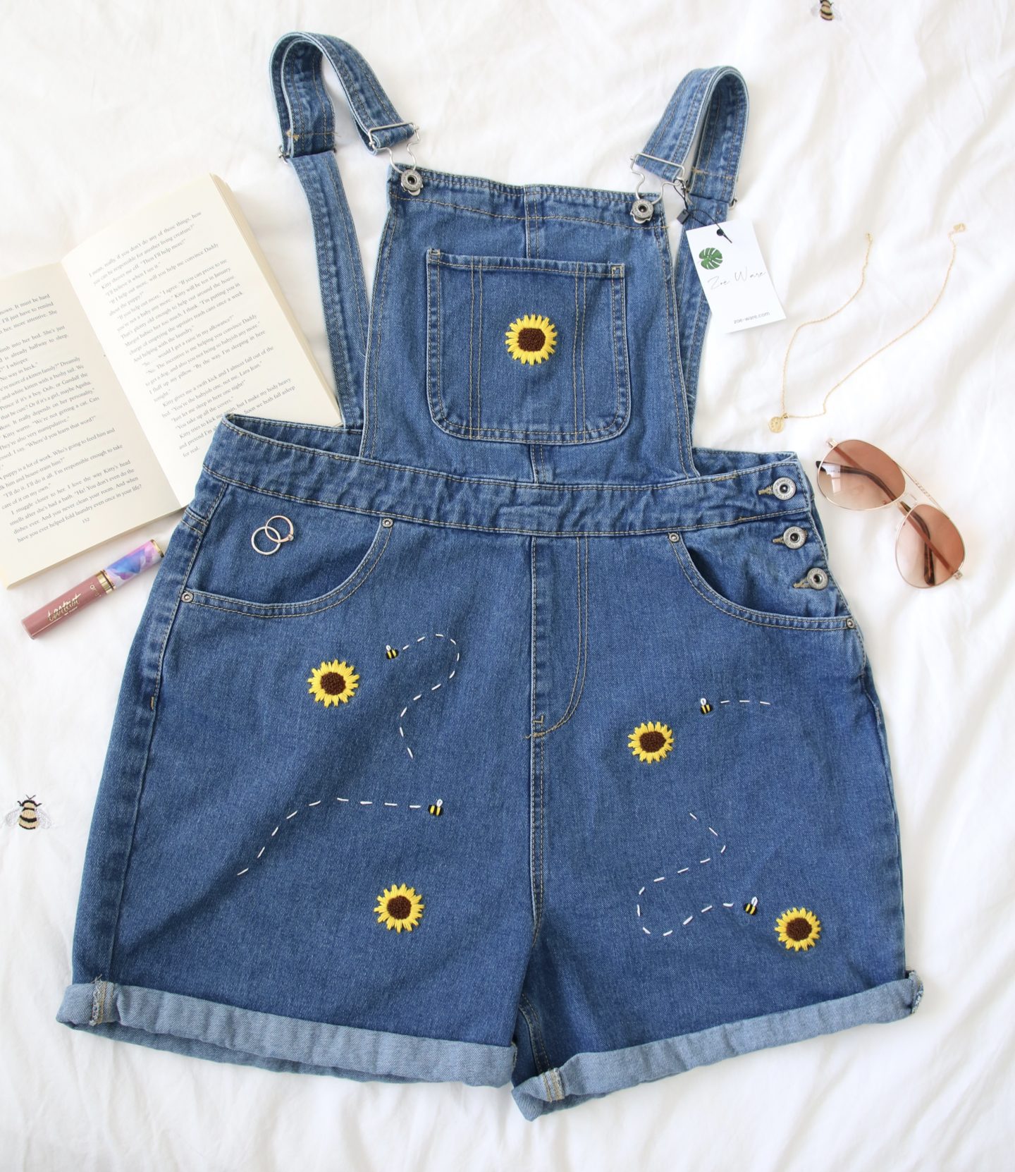 Flatlay of the Winnie overalls embroidered with sunflowers and bees
