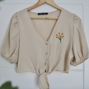 A beige tie up blouse hand embroidered with a bunch of sunflowers
