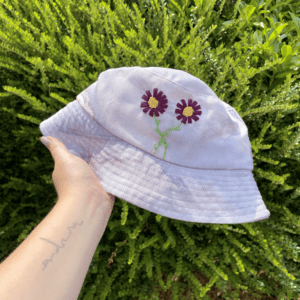 hand holding purple bucket hat hand embroidered with purple cosmos flowers