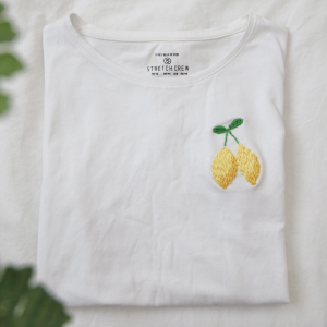 A folded up white t-shirt hand embroidered with lemons
