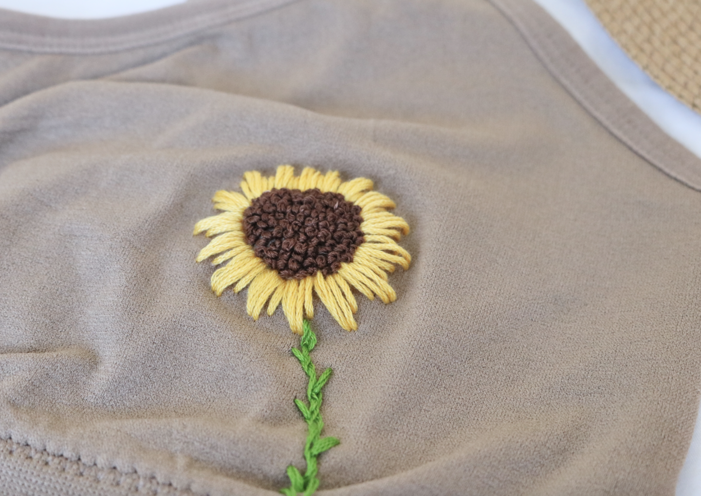 A brown bralette hand embroidered with sunflowers