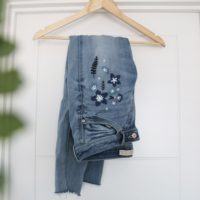 Blue skinny jeans folded up showing the dark blue embroidered flowers