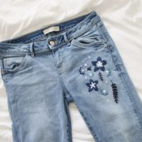 Close up of the dark blue embroidered flowers on the jeans