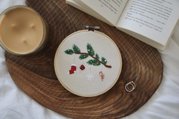 A hand embroidered 6 inch hoop with a snowy branch and hanging ornaments