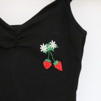 close up of embroidered strawberries on black bodysuit