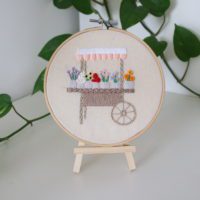 Flower cart hoop displayed on wooden embroidery hoop stand