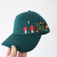 Overview of the whole green cap with embroidered flowers and mushrooms