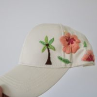 close up of cream hat with a palm tree and pink and orange hibiscus flower