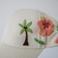 close up of embroidered palm tree on a cream cap