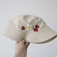 cream bucket hat hand embroidered with a white daisy and 3 red strawberries