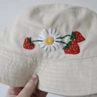 Close up of bucket hat showing the embroidered daisy and strawberries