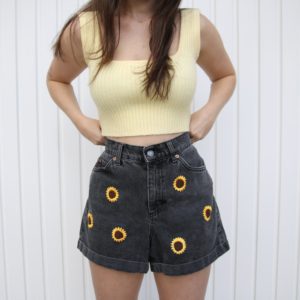 close up of girl wearing sunflower shorts and yellow top