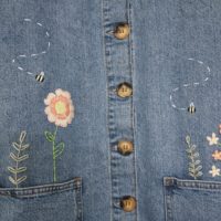 close up of the pink florals, greenery, and bee embroidery