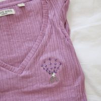 close up of the hand embroidered lavender on a purple top