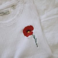 a detailed red poppy hand embroidered on a white top