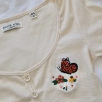 Close up of an embroidered orange butterfly and flowers