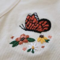 Close up of the stitch work on the orange, yellow and white flowers