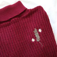 Hand embroidered rosemary and daisies on a red turtle-neck jumper