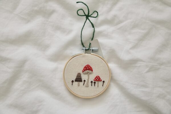 A 3 inch hoop hand embroidered with a red toadstool mushroom and fungi