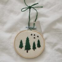 a 3 inch decor hoop hand embroidered with 4 trees and birds flying in the sky