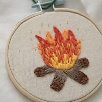 close up of hand embroidered campfire with gold flecks