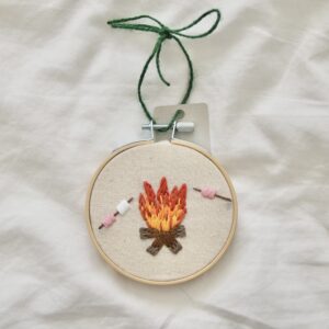 A 3 inch decor hoop hand embroidered with a fire and roasting marshmallows