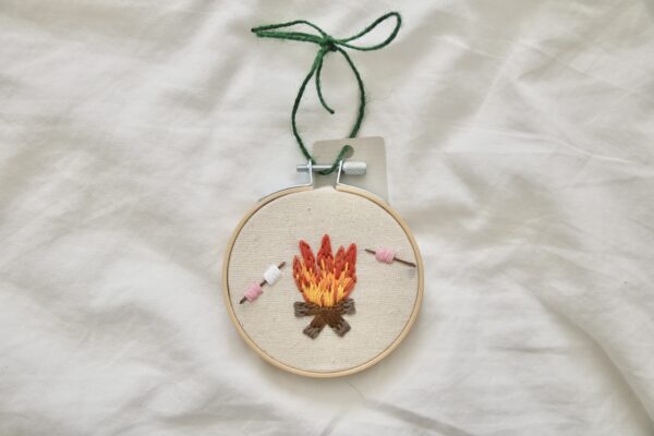 A 3 inch decor hoop hand embroidered with a fire and roasting marshmallows