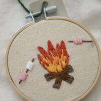 Close up of a 3 inch decor hoop hand embroidered with a fire and roasting marshmallows