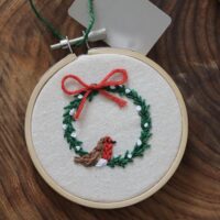 Close up of hand embroidered wreath and robin