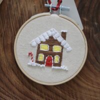 close up of a hand embroidered gingerbread house with a candy cane