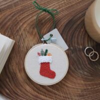 christmas tree decoration hand embroidered with a red stocking and presents spilling out the top