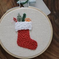 Close up of a hand embroidered red stocking with presents spilling out the top