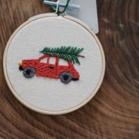 Close up of hand embroidered red car and tree on top