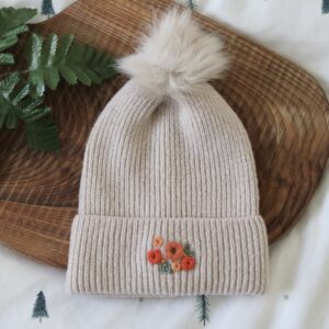 Cream pom pom beanie hand embroidered with orange roses and green leaves
