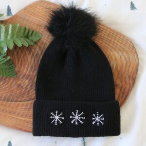 Black pom pom beanie hand embroidered with 3 white snowflakes