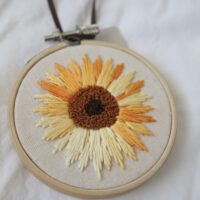 Hand embroidered sunflower on a wooden hoop.