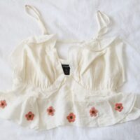 A floaty white crop top hand embroidered with pink cherry blossom