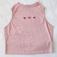 a pink and white top hand embroidered with 3 red hearts in the centre